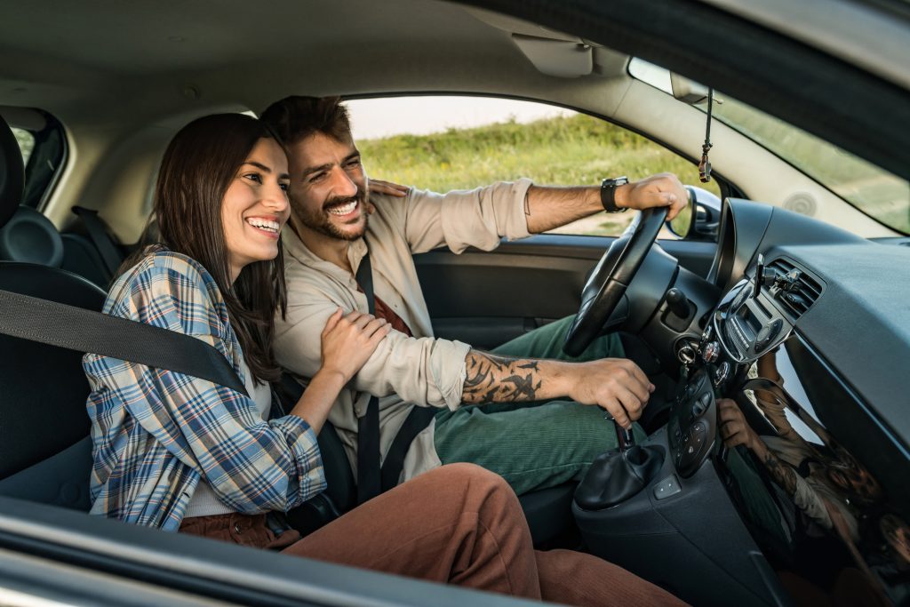 Pareja sonriente viaja en auto durante un trayecto cotidiano