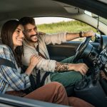 Pareja sonriente viaja en auto durante un trayecto cotidiano