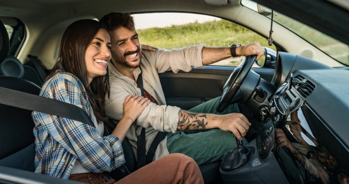 Pareja sonriente viaja en auto durante un trayecto cotidiano