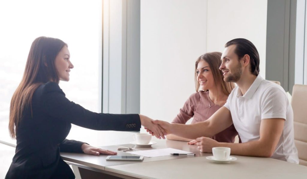 Corredor de seguros cerrando un acuerdo con clientes en un entorno profesional de oficina