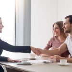 Corredor de seguros cerrando un acuerdo con clientes en un entorno profesional de oficina