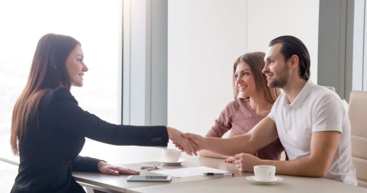 Corredor de seguros cerrando un acuerdo con clientes en un entorno profesional de oficina