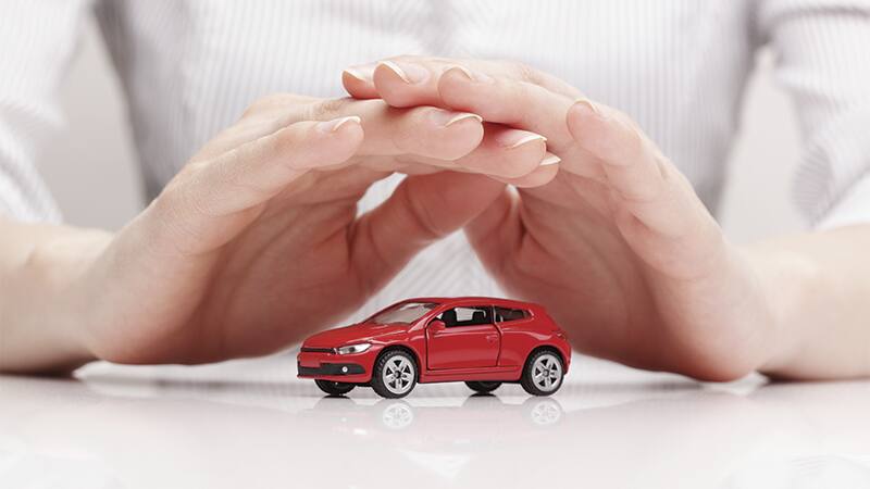 Manos protegiendo un auto en miniatura que representan qué es el interés asegurable