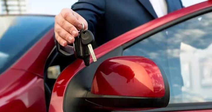 Ejecutivo entregando llaves de un vehículo rojo luego de concretar la Transferencia del auto ante el registro automotor.