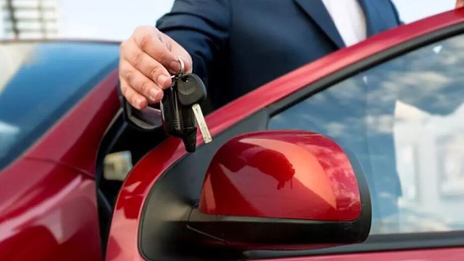 Ejecutivo entregando llaves de un vehículo rojo luego de concretar la Transferencia del auto ante el registro automotor.