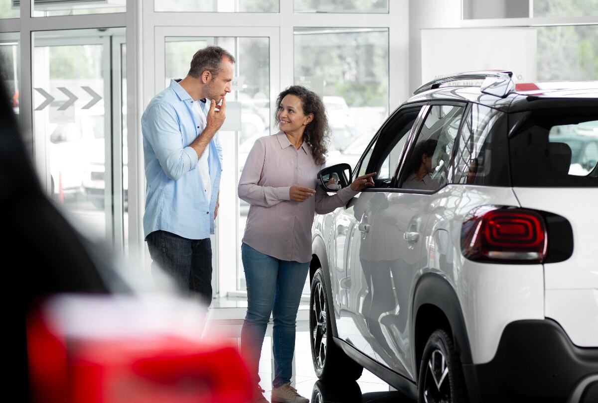 Pareja analizando un vehículo en concesionaria como parte del proceso de comparar seguros de auto en Uruguay antes de la compra.