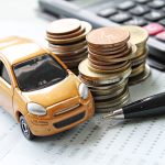 Auto en miniatura junto a monedas y calculadora, ilustrando el análisis para determinar si una empresa está pagando caro el seguro automotor.