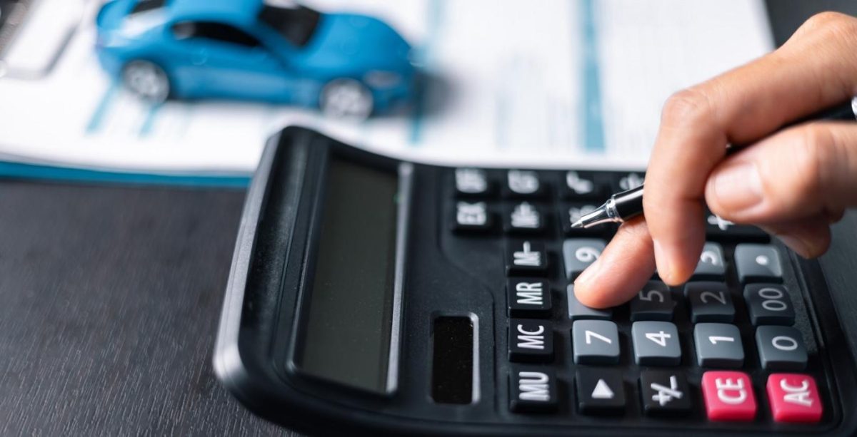 Mano usando calculadora con modelo de auto al fondo, revisando si la compañía está pagando caro el seguro según su estructura de costos.